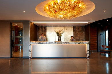 This is an example of a large foyer in London with brown walls, ceramic flooring and grey floors.