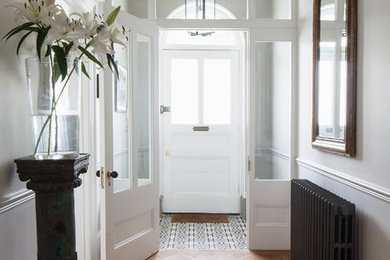 Photo of a large traditional foyer in Sussex with grey walls, light hardwood flooring, a single front door, a white front door, brown floors, a coffered ceiling and panelled walls.