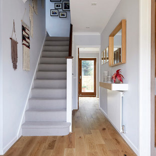 This is an example of a classic hallway in London with grey walls, light hardwood flooring and beige floors.