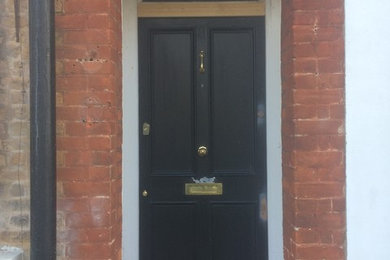 Photo of a medium sized victorian front door in Kent with white walls, concrete flooring, a single front door and a black front door.