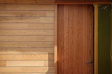 This is an example of a medium sized contemporary front door in Wiltshire with brown walls, medium hardwood flooring, a single front door, a medium wood front door and brown floors.