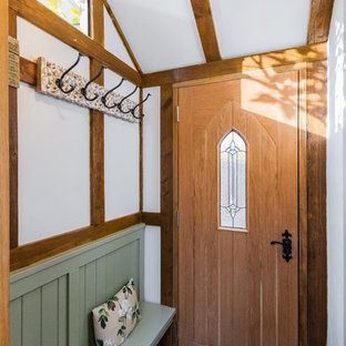 This is an example of a farmhouse entrance in London with white walls, a single front door, a medium wood front door and grey floors.