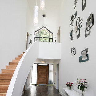 This is an example of a contemporary foyer in Other with white walls, a single front door, a medium wood front door and grey floors.