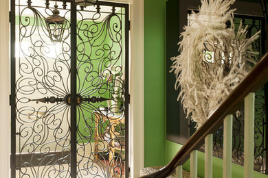 Réalisation d'une entrée bohème de taille moyenne avec un mur vert, un sol en travertin et une porte métallisée.