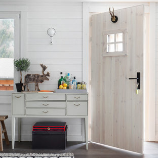 Cette image montre une porte d'entrée nordique avec un mur blanc, un sol en bois brun, une porte simple et une porte en bois clair.