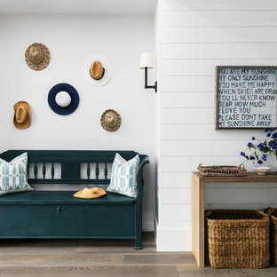 This is an example of a beach style entrance in London with white walls and light hardwood flooring.
