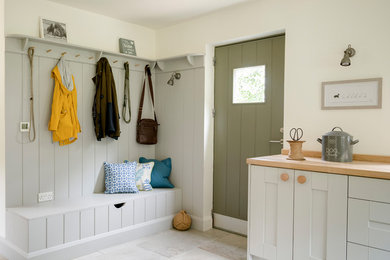 Aménagement d'une entrée campagne avec un vestiaire, un mur blanc, une porte simple, une porte verte et un sol beige.