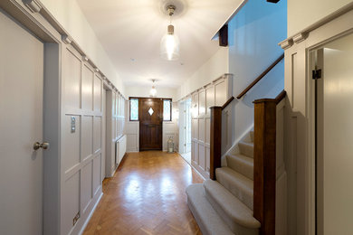 Design ideas for a medium sized traditional hallway in London with grey walls, medium hardwood flooring, a single front door and a dark wood front door.