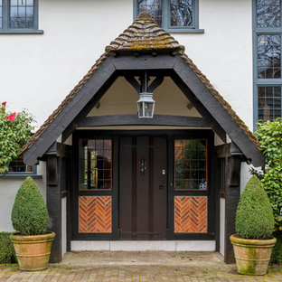 Inspiration for a farmhouse front door in Surrey with white walls, a single front door, a dark wood front door, brick flooring and brown floors.