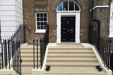 Large classic front door in London with multi-coloured walls, limestone flooring, a single front door, a black front door and beige floors.