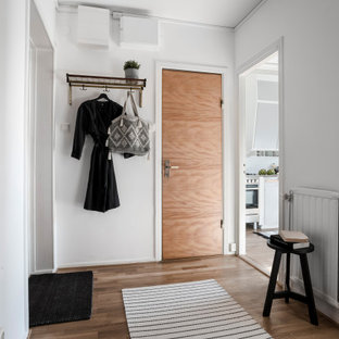 Idéer för en mellanstor skandinavisk hall, med vita väggar, mellanmörkt trägolv, en enkeldörr, mellanmörk trädörr och brunt golv