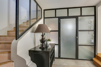 На фото: фойе среднего размера в стиле неоклассика (современная классика) с серыми стенами, гранитным полом, одностворчатой входной дверью, черной входной дверью и бежевым полом