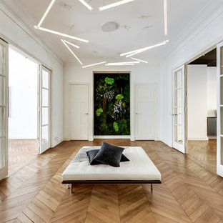 Idée de décoration pour un grand hall d'entrée design avec un mur blanc, un sol en bois clair et un sol beige.