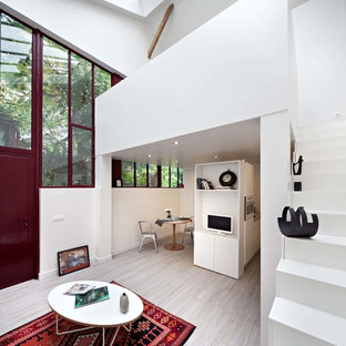 Exemple d'un hall d'entrée tendance de taille moyenne avec un mur blanc, un sol en bois clair, une porte simple et une porte rouge.