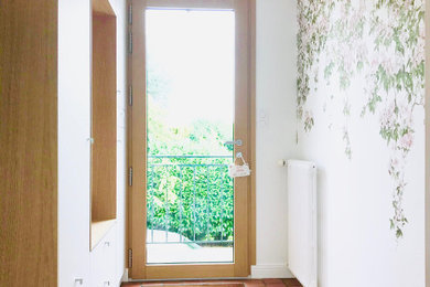 Idee per un piccolo ingresso chic con pareti bianche, pavimento in terracotta, una porta singola, una porta in legno chiaro, pavimento rosso e carta da parati