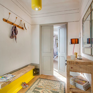 Inspiration pour une entrée bohème de taille moyenne avec un mur beige, un sol en bois clair et un vestiaire.
