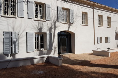 Réalisation d'un grand hall d'entrée méditerranéen avec un mur blanc, un sol en carrelage de céramique, une porte double, une porte métallisée et un sol beige.