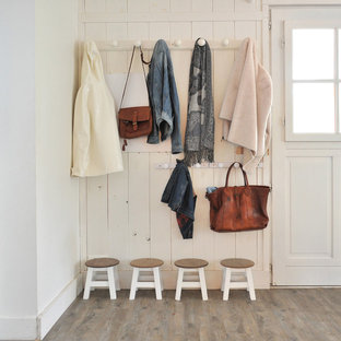 Aménagement d'une entrée campagne avec un vestiaire, un mur blanc, un sol en bois foncé, une porte simple et une porte blanche.