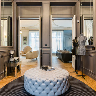 Cette image montre un vestibule traditionnel de taille moyenne avec un mur gris, un sol en bois brun et une porte grise.