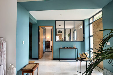 Inspiration pour un hall d'entrée design avec un mur bleu, un sol en carrelage de céramique, une porte simple, une porte en bois clair et un sol beige.