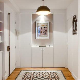 Foto di un grande ingresso con vestibolo minimal con pareti bianche e pavimento in legno massello medio