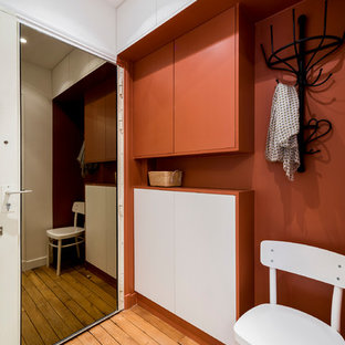 Réalisation d'un hall d'entrée urbain de taille moyenne avec un mur rouge, un sol en bois clair et une porte simple.