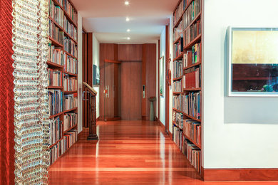 Idee per un grande corridoio moderno con pareti bianche, pavimento in legno massello medio, una porta in legno bruno e una porta scorrevole