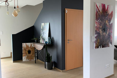 ストラスブールにある低価格の中くらいなコンテンポラリースタイルのおしゃれな玄関ロビー (黒い壁、淡色無垢フローリング、白いドア、ベージュの床) の写真