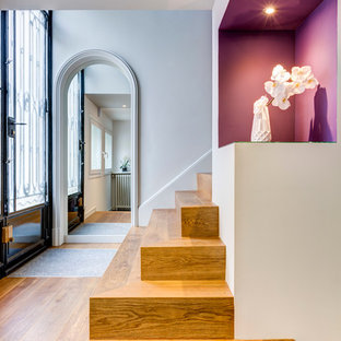 Inspiration pour un grand hall d'entrée design avec un mur blanc, un sol en bois brun, une porte double et une porte noire.