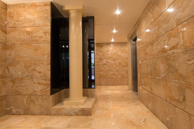 Imagen de distribuidor clásico grande con paredes beige, suelo de mármol, puerta doble y puerta marrón