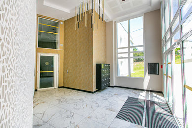 Aménagement d'un hall d'entrée classique avec un mur beige, un sol en marbre, une porte blanche, un sol blanc et du papier peint.