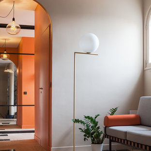 Cette image montre un grand hall d'entrée méditerranéen avec un mur gris, une porte simple, une porte orange et un sol beige.