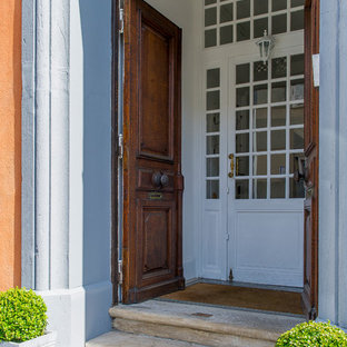 Réalisation d'une porte d'entrée tradition avec un mur gris, une porte double et une porte en bois foncé.