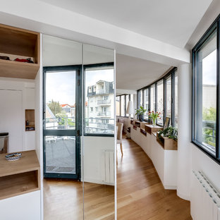 Modern inredning av en stor foajé, med vita väggar, plywoodgolv, en vit dörr och beiget golv