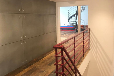 Imagen de distribuidor moderno grande con paredes grises, suelo de madera oscura, puerta simple, puerta blanca y suelo multicolor