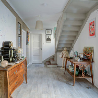 Aménagement d'une entrée bord de mer avec un couloir, un mur blanc, un sol en bois clair, une porte simple, une porte blanche et un sol gris.