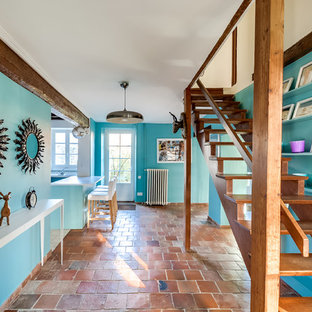 Exemple d'un grand hall d'entrée éclectique avec un mur bleu et un sol en carreau de terre cuite.
