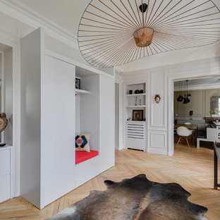 Cette photo montre un hall d'entrée tendance avec un mur gris et un sol en bois clair.