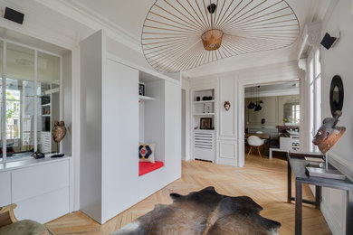 Cette photo montre un hall d'entrée tendance avec un mur gris et parquet clair.