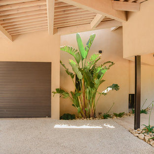Cette photo montre une porte d'entrée tendance avec un mur beige, béton au sol, une porte simple, une porte en bois brun et un sol gris.