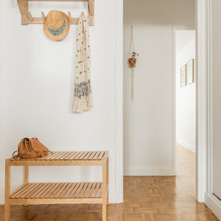 Aménagement d'un hall d'entrée scandinave avec un mur blanc, un sol en bois clair, un sol marron et une porte blanche.