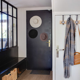 Idée de décoration pour une entrée design de taille moyenne avec un couloir, un mur blanc, une porte simple, une porte noire, un sol marron et un sol en carrelage de céramique.