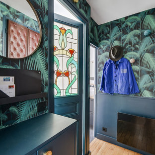 Réalisation d'une entrée design avec un mur multicolore, un sol en bois brun, une porte simple, une porte bleue et un sol beige.
