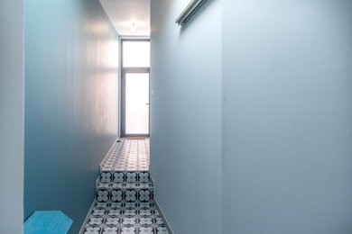 Idées déco pour une petite porte d'entrée contemporaine avec un mur bleu, un sol en carrelage de céramique, une porte pivot, une porte grise et un sol gris.