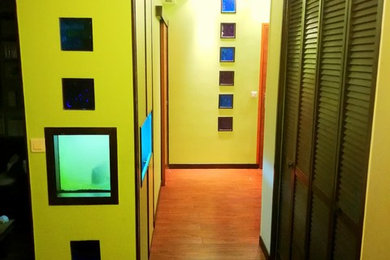 Idées déco pour un petit hall d'entrée exotique avec un mur vert, un sol en bois brun et une porte en bois brun.