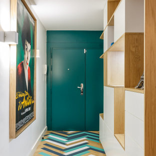 Cette image montre une entrée design avec un mur blanc, un sol en bois peint, une porte simple, une porte verte et un sol multicolore.