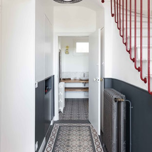 Réalisation d'une entrée design avec un couloir, un mur blanc et un sol multicolore.