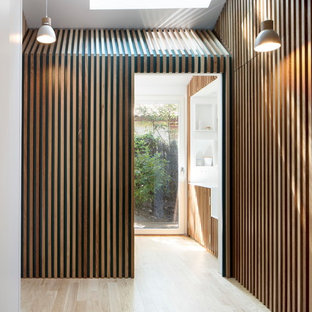 Idées déco pour une entrée contemporaine avec un sol en bois clair et un sol beige.