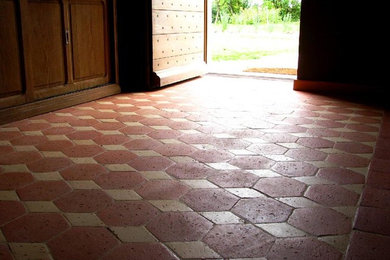 Cette image montre une entrée traditionnelle avec tomettes au sol et un sol rouge.