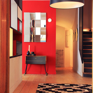 Inspiration pour un hall d'entrée design de taille moyenne avec un mur rouge et un sol en bois clair.